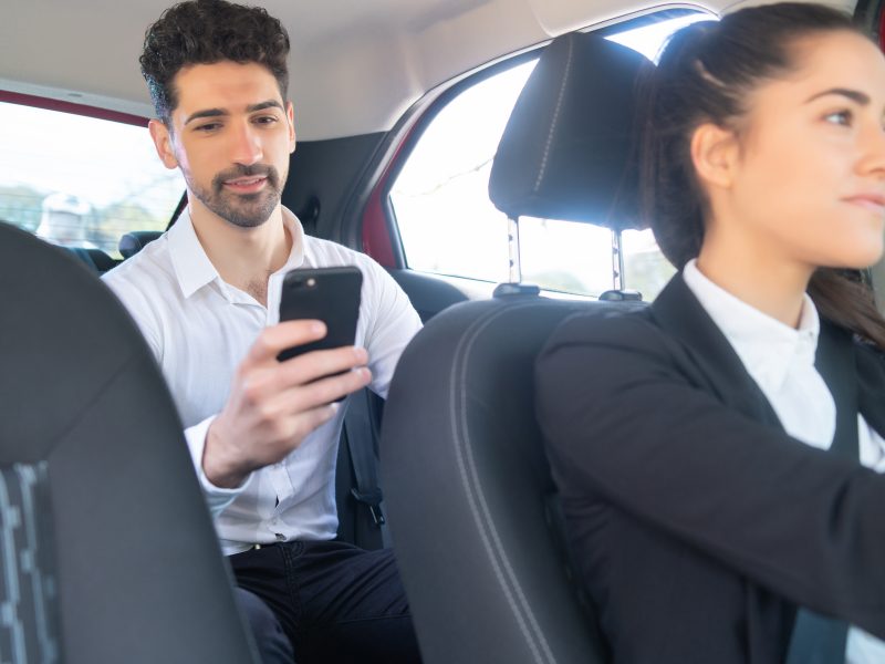 Portrait of businessman using his mobile phone on way to work in a cab. Business concept.